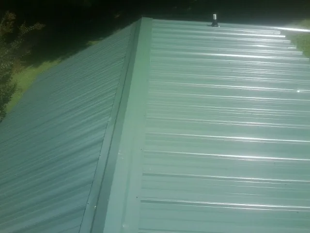 New green metal panels meeting at the ridge of a roof — Flat Roof Repair work by our crew in Tuckahoe