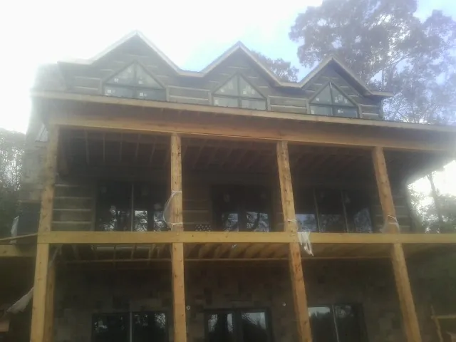 Dormers and porch framing on a large log home under construction — Roof Coating work by our crew in Tuckahoe