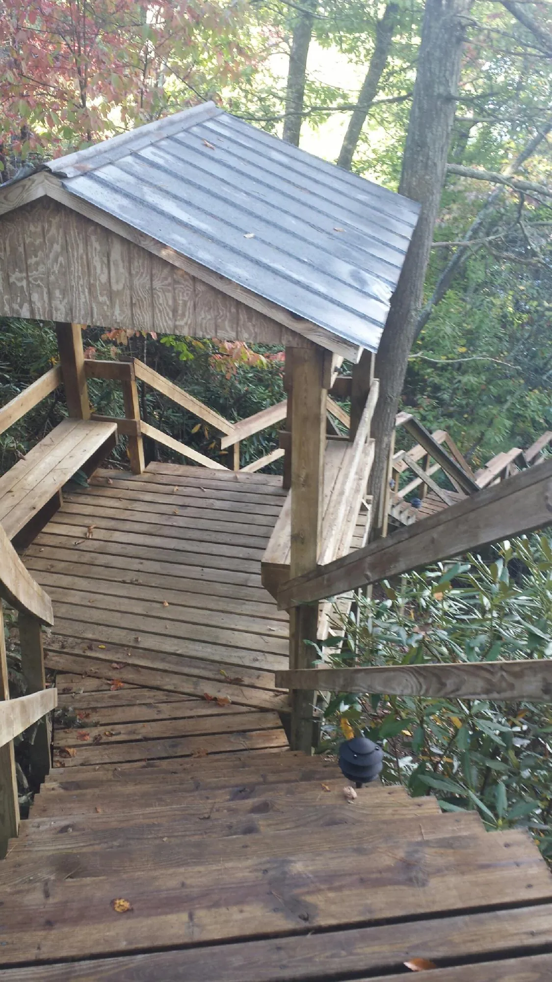 Metal roofed shelter over wooden steps on a wooded walkway — Skylight Repair & Installation work by our crew in Tuckahoe