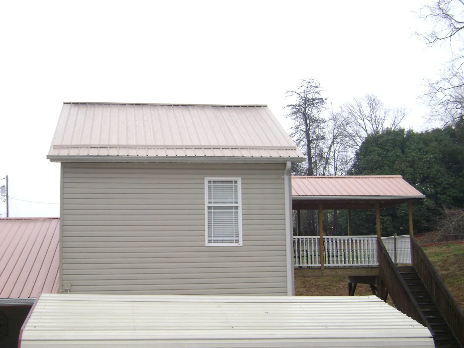 Tan metal roofs on a two story addition and attached porch, from a Roof Replacement job in Tuckahoe