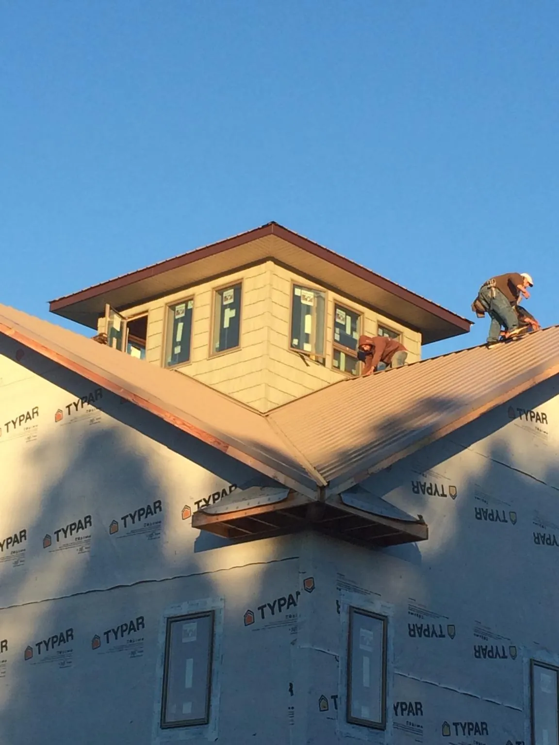 Roofers working around a rooftop cupola on a new metal roof at sunset — Roof Waterproofing in Tuckahoe by Roofing Brothers
